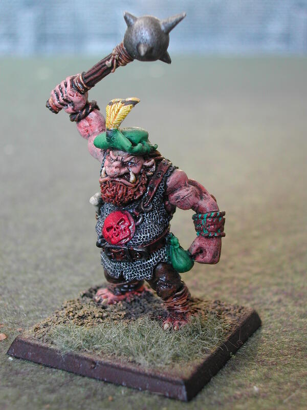 Painted fantasy ogre miniature raising a spiked mace on a square base.