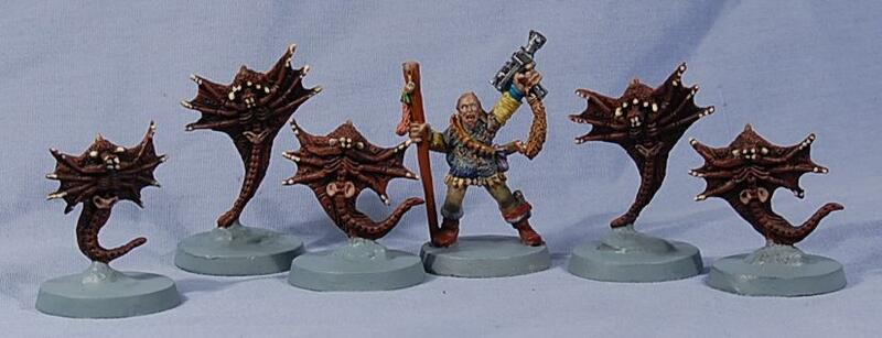 Five painted fantasy miniatures on white bases, with a warrior flanked by spiky creatures.