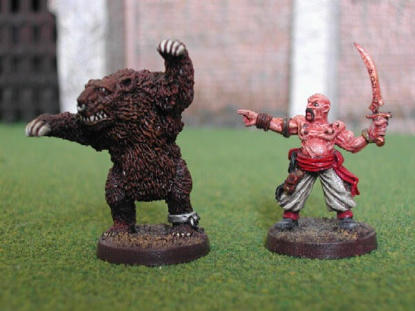 Two painted miniatures on grass: a dark beast and a red warrior with raised sword.
