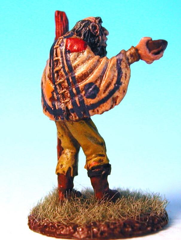 Photograph of a painted figurine in a striped poncho, holding a bowl on grass.